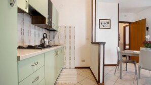 Una cocina moderna con armarios verde claro, una estufa a gas y un tapete a rayas.