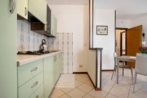 A modern kitchen with light green cabinets, a gas stove, and a striped rug.