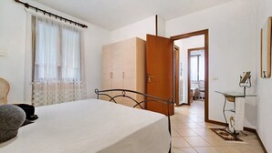 Un dormitorio con cama, armario, escritorio con espejo y silla.