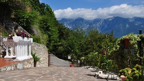 Un chemin de pierres menant à une porte, bordé de verdure et offrant une vue sur la montagne.