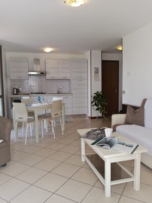 Ein modernes Wohnzimmer mit einem weißen Sofa, einem Couchtisch und einem Essbereich mit Tisch und Stühlen.