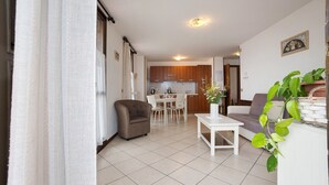 Un salon comprenant un canapé, une table basse, un fauteuil et un coin repas avec une table et des chaises.