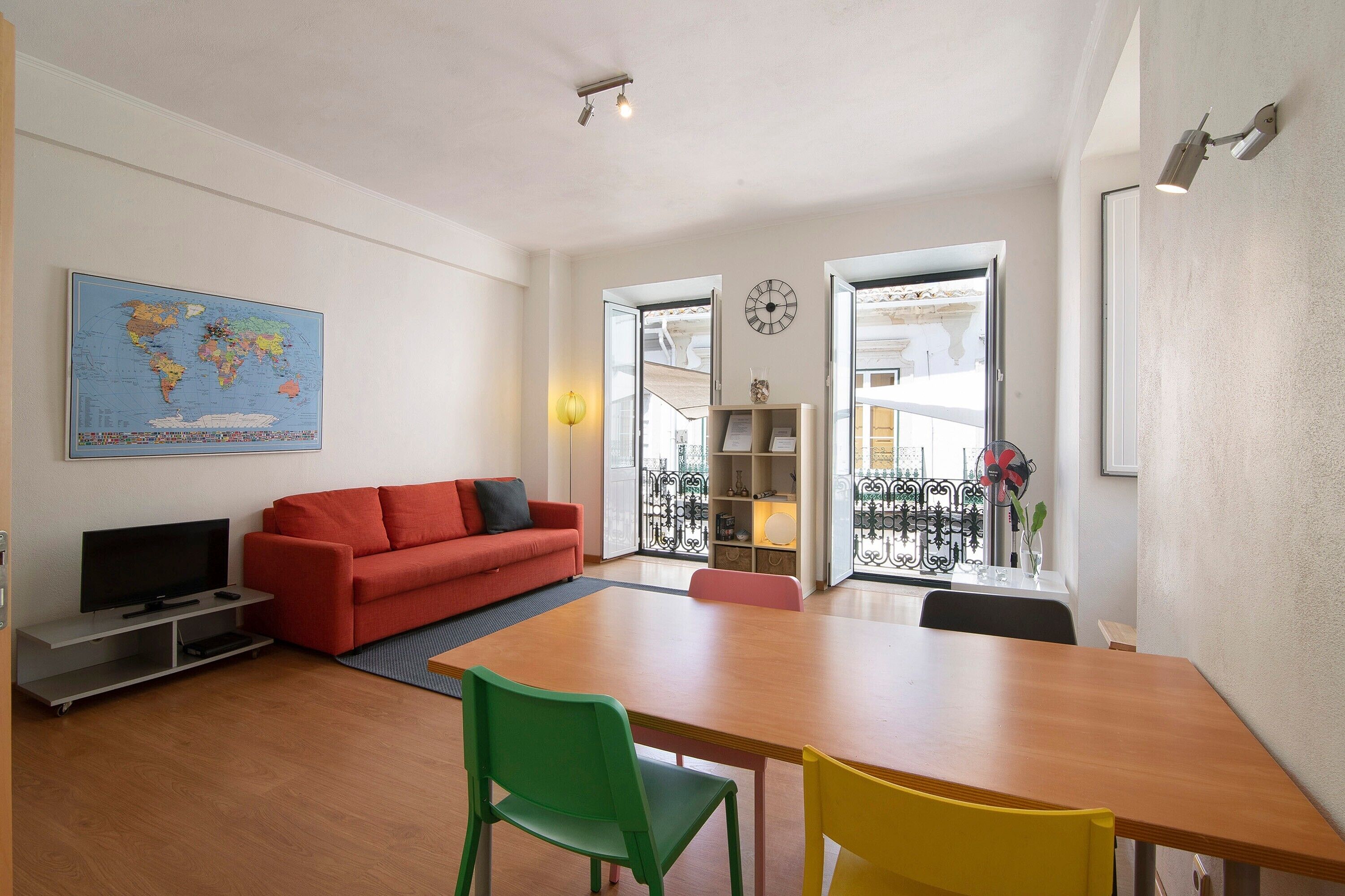 Un salon moderne avec un canapé rouge, une table à manger en bois et un fauteuil vert.