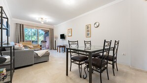 Una sala de estar moderna con sofá, mesa de comedor, sillas y televisor.