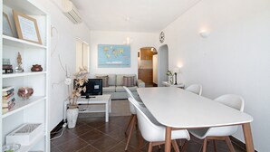 A modern living room with a dining area, a sofa, a coffee table, a bookshelf, and a world map on the wall. - Ocean View Apartment with Sea View, Wi-Fi (Armação de Pêra)