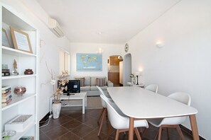 Una sala de estar moderna con comedor, un sofá, una mesa de centro, una estantería y un mapa mundial en la pared.
