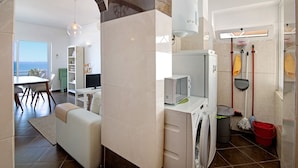 A modern kitchen with a microwave, sink, and cleaning supplies. - Ocean View Apartment with Sea View, Wi-Fi (Armação de Pêra)