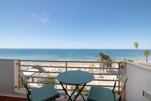 Varanda com mesa e cadeiras, com vista para a praia e o oceano.