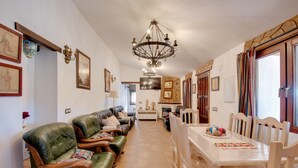 A dining area with a table, chairs, a chandelier, and a sofa. - Pet-Friendly Vacation Home 'Miramar' with Garden, Private Pool, Terrace & Wi-Fi (Almogia)