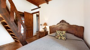 A bedroom with a wooden headboard, a bed with a floral pillow, a nightstand with a lamp, and a wooden staircase. - Pet-Friendly Vacation Home 'Miramar' with Garden, Private Pool, Terrace & Wi-Fi (Almogia)