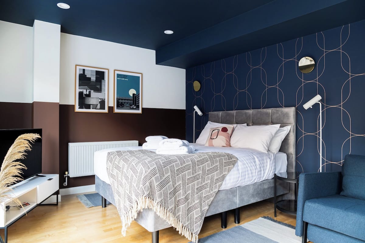 Un dormitorio moderno con una cama, mesitas de noche, un televisor y obras de arte en la pared.