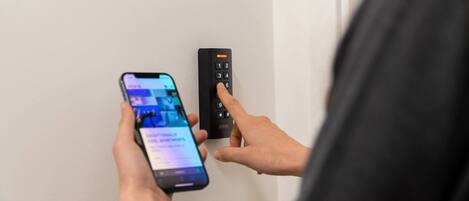 Una persona usando un teléfono inteligente y un teclado para ingresar a una habitación.