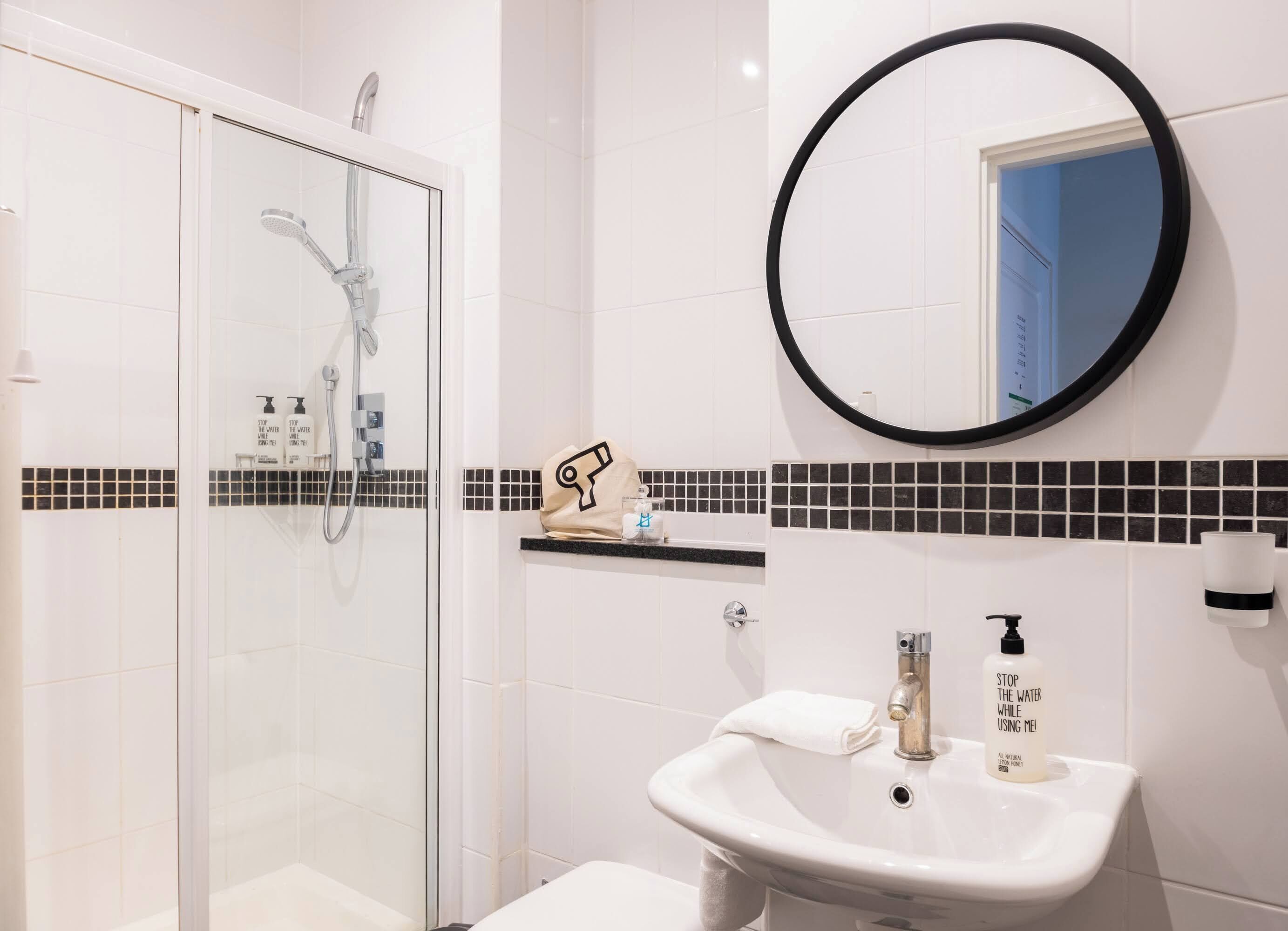 A bathroom with a glass-enclosed shower, a sink with a mirror, and a towel rack.