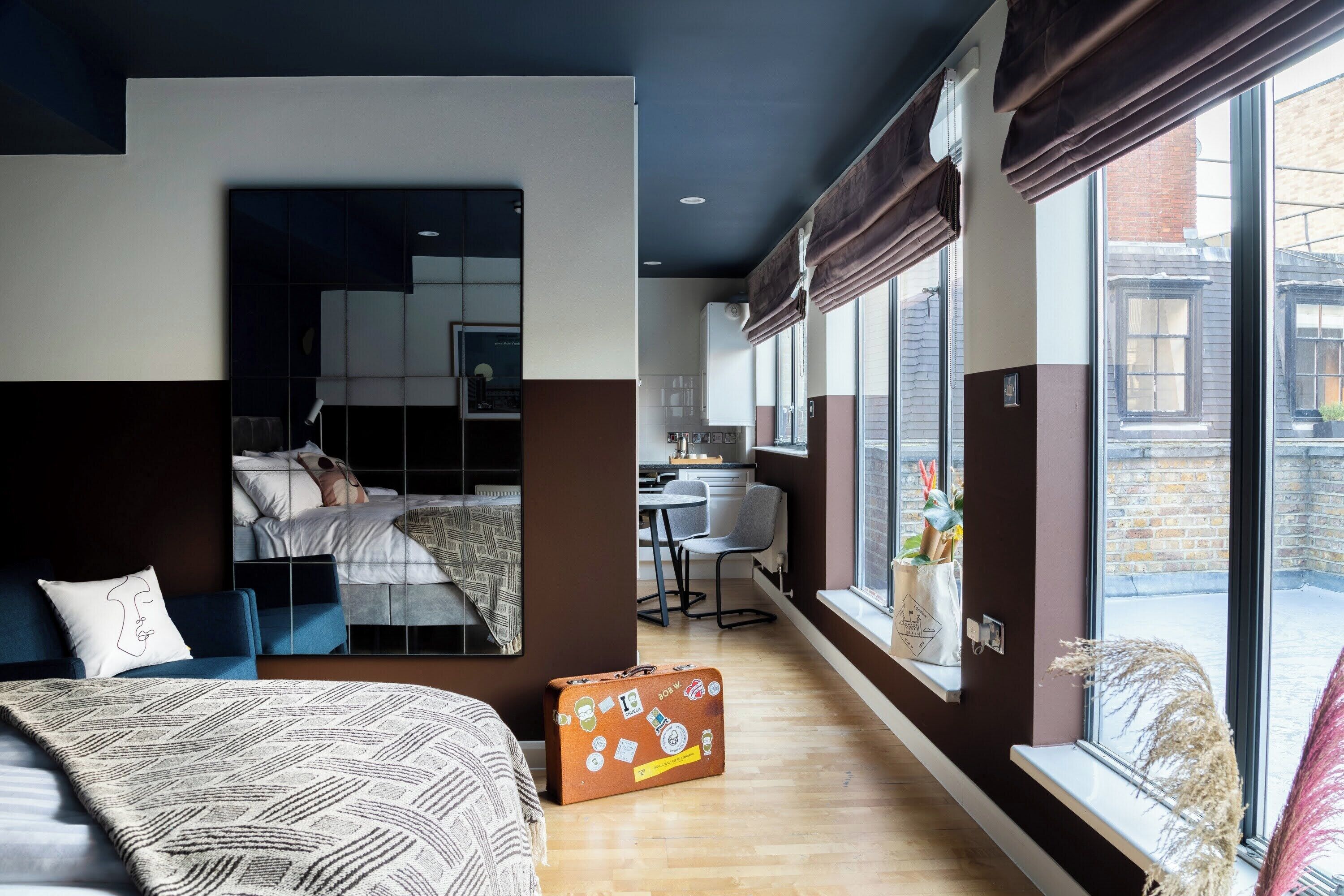 A modern hotel room with a bed, a desk, and a view of the street.