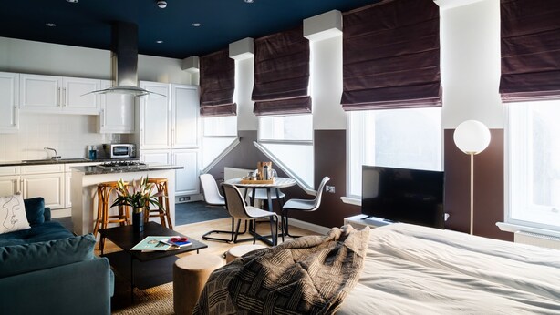 Una habitación de hotel moderna con kitchenette, comedor y una cama grande.