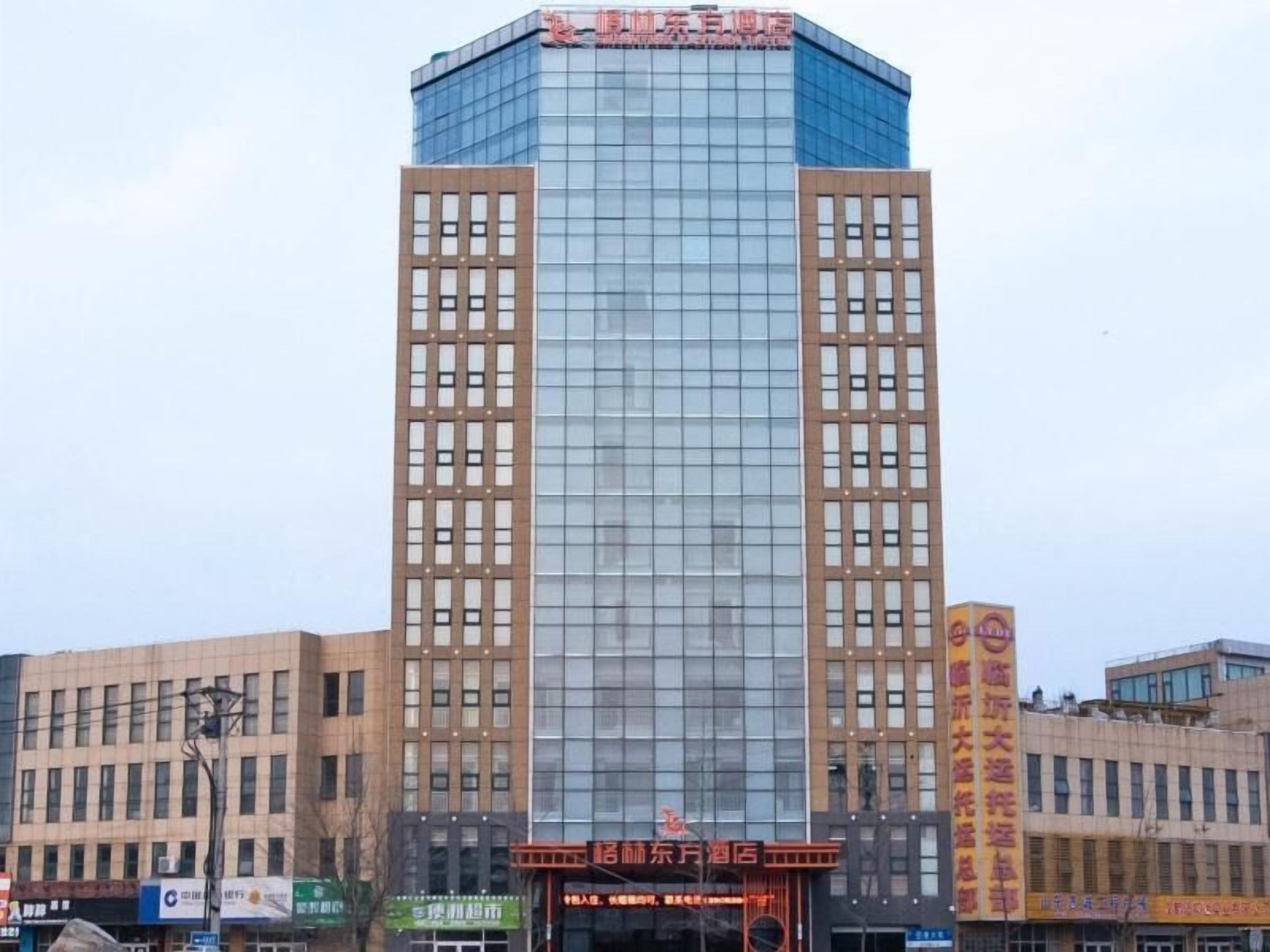 Un grand immeuble moderne à la façade en verre, sur lequel on peut lire une enseigne indiquant qu’il s’agit d’un hôtel.