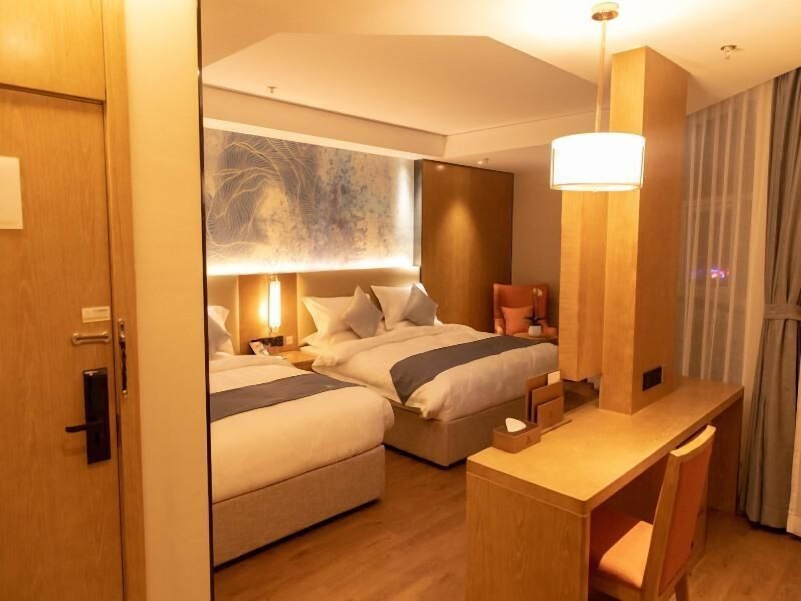 Habitación de hotel con dos camas, un escritorio y una obra de arte grande en la pared.