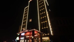 Ein Hotel mit modernem Design, das eine auffällige Eingangszone mit beleuchteter Beschilderung zeigt.