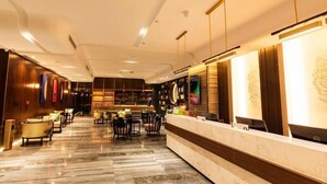 Eine moderne Hotelhalle mit Empfangsschalter, Sitzgelegenheit und einer großen Bücherwand.