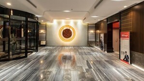 Eine moderne Lobby mit Marmorboden, einer Glaselevator und einer runden Wandleuchte.