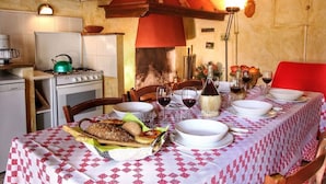 Zona pranzo con tavolo apparecchiato, un fornello e un ombrello rosso.
