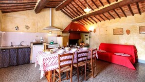 Una cucina accogliente con un tavolo da pranzo per quattro persone, un divano rosso e un pavimento piastrellato.