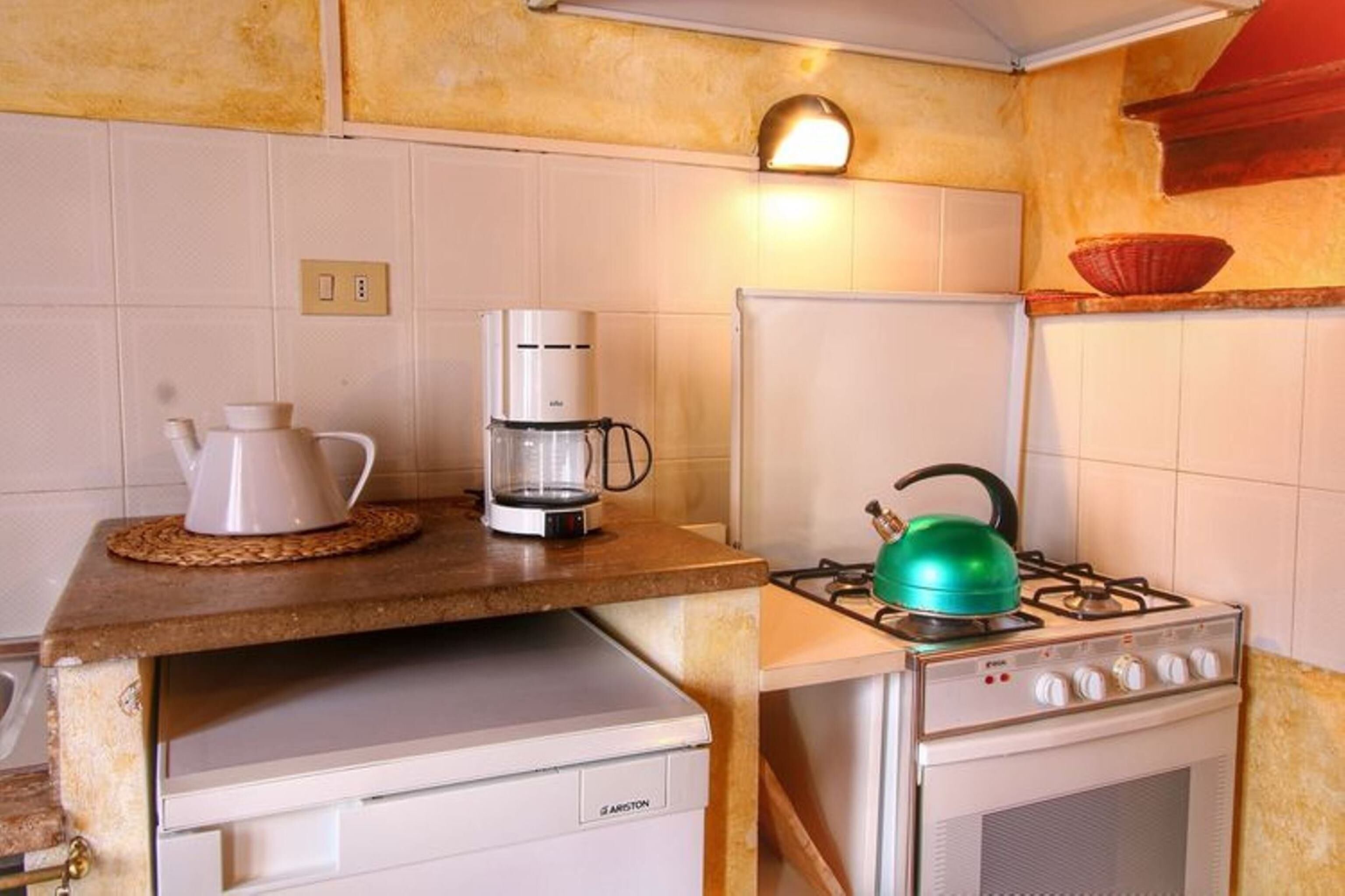A compact kitchen with a gas stove, a coffee maker, and a refrigerator.