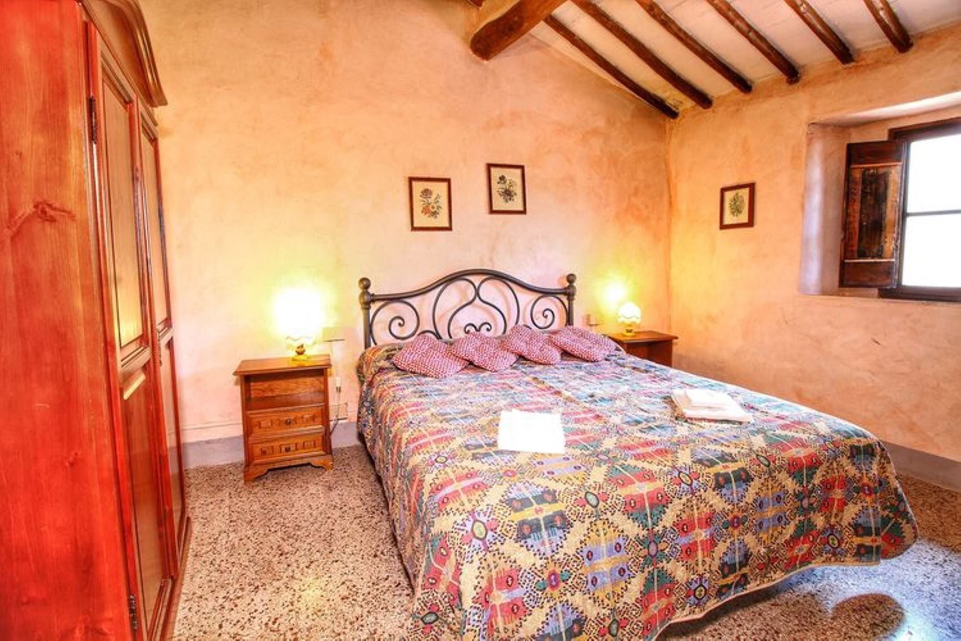 Quarto com cama, mesas de cabeceira de madeira e janela.