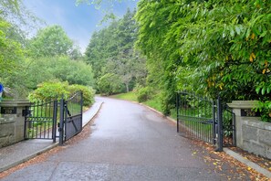 Enter the serene WELLWOOD 250 estate through its traditional black gate, surrounded by lush greenery.