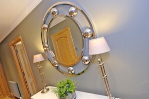 Reflect on serenity in this stylish room, featuring a large mirror, floor lamps, and a potted plant.