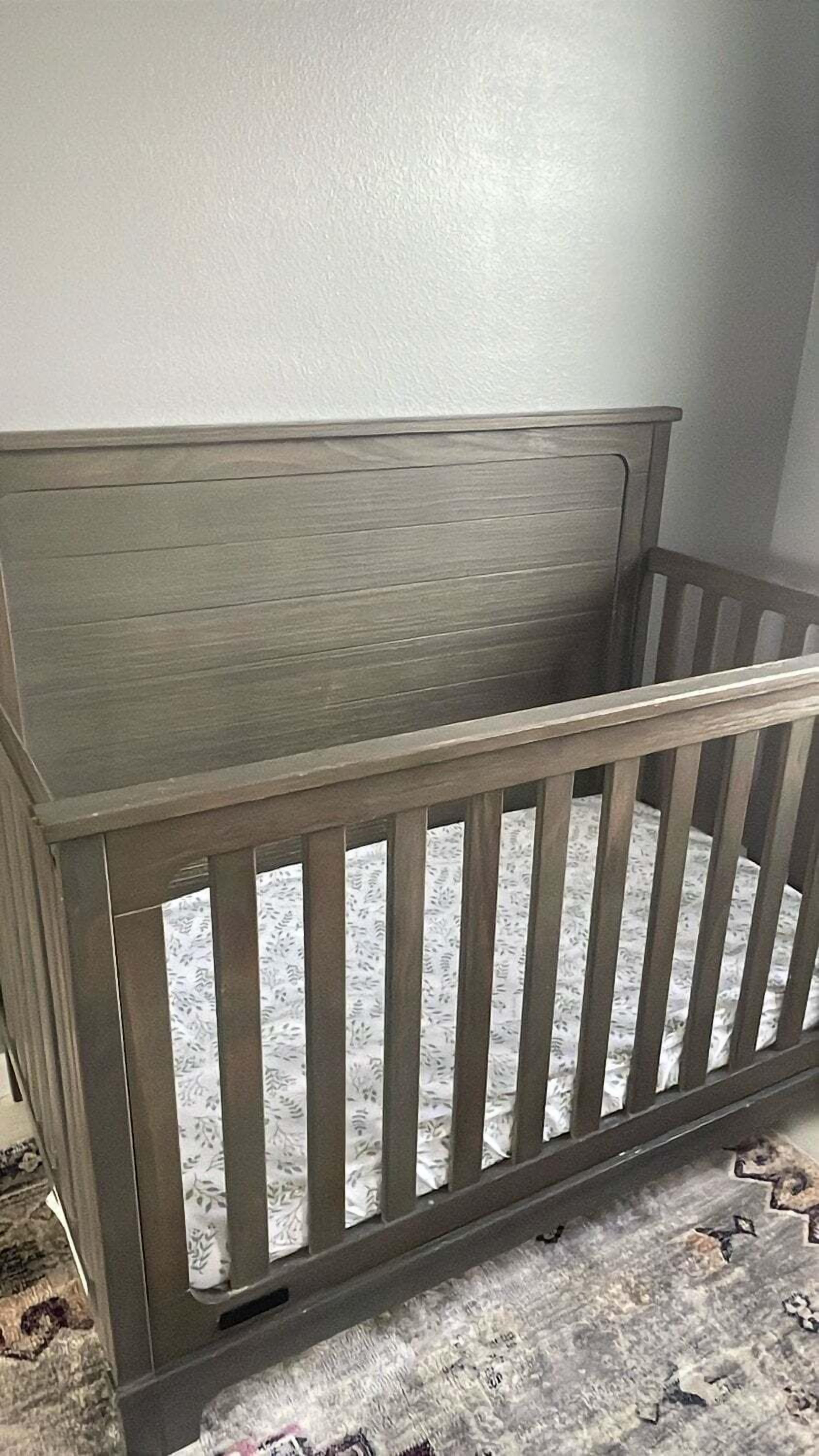 A wooden crib with vertical slats, a solid headboard, and a footboard.