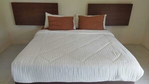 Ein Standard-Hotelzimmer mit einem großen Bett, zwei Kissen und einem Holzkopfbrett.