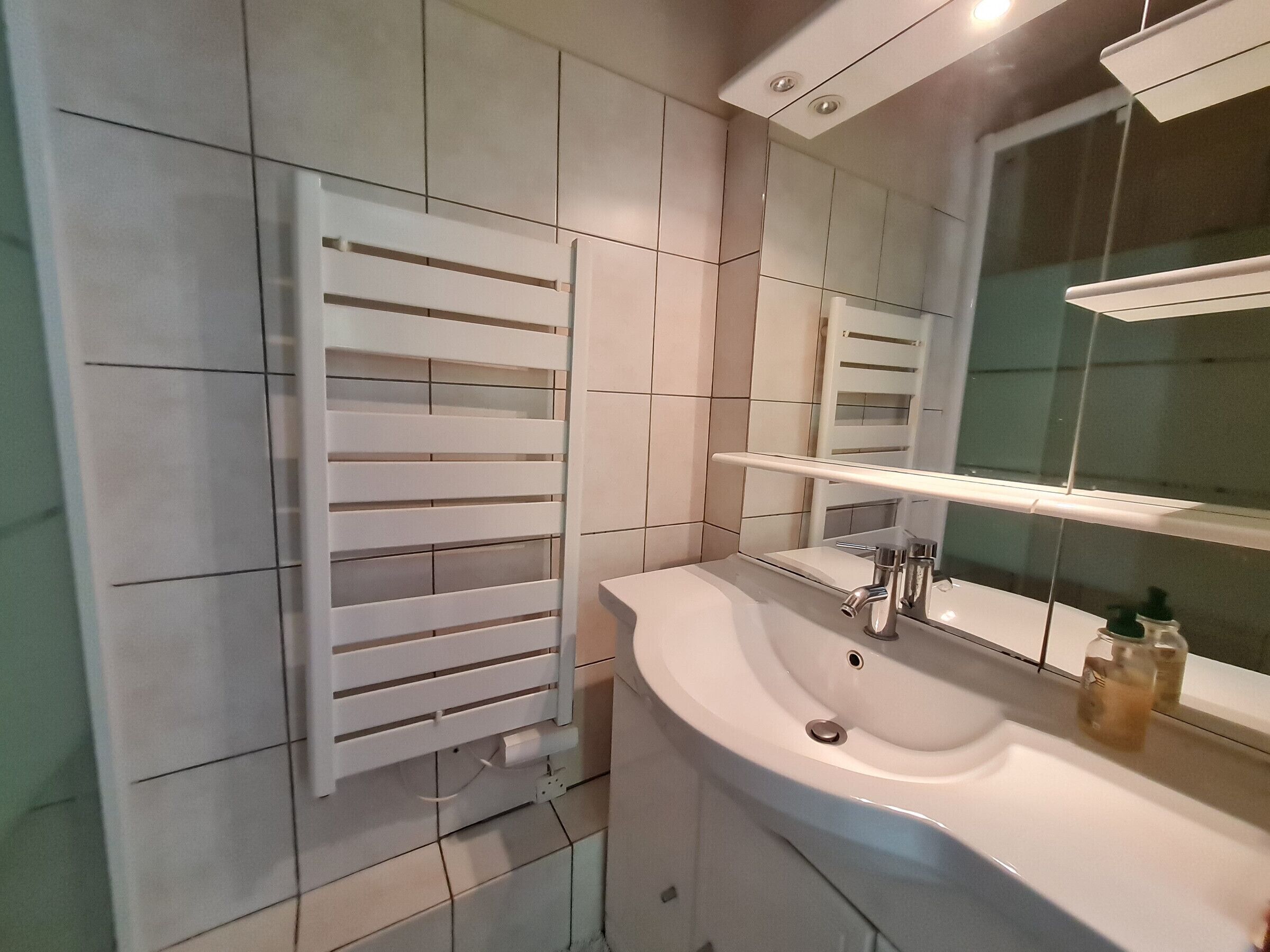 A bathroom with a white sink, mirror, and towel rack.