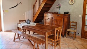 A dining area with a wooden table, benches, and chairs. A wooden staircase leads to an upper level.