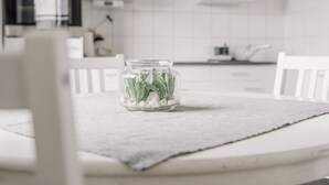 Une cuisine avec des armoires blanches, un comptoir et un bocal en verre contenant des plantes vertes, posé sur une table.