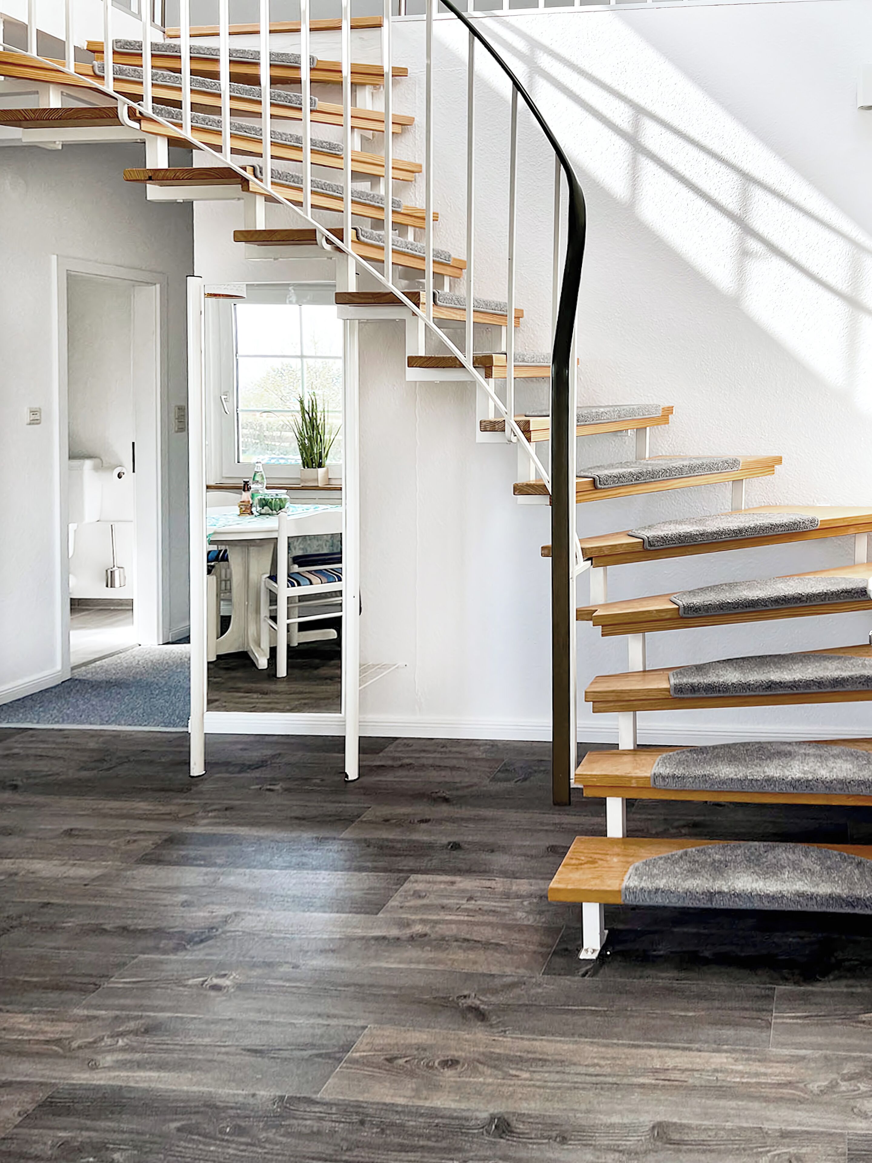 A modern staircase with wooden steps and white railings, leading to an upper floor.