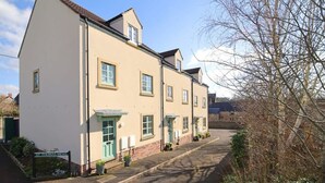 A row of traditional buildings with a sign reading "St. Thomas Mews." - Townhouse with Views of Wells Cathedral (Wells)