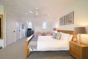 A bedroom with a bed, bedside tables, a desk, two chairs, a ceiling fan, and artwork on the wall. - Townhouse with Views of Wells Cathedral (Wells)