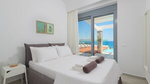 Une chambre avec un lit, une table de chevet et une vue sur la piscine et l’océan.