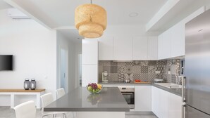Une cuisine moderne dotée d’un îlot central, d’appareils électroménagers en acier inoxydable et d’un revêtement mural décoratif.