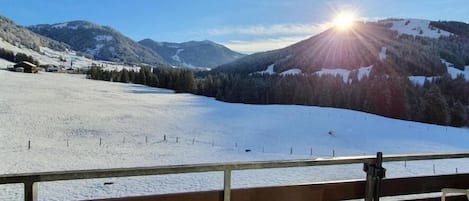 Eine verschneite Berglandschaft mit klarem Himmel und strahlender Sonne.