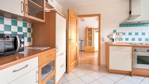 A kitchen with wooden cabinets, a microwave, a coffee maker, and a tiled backsplash. - Apartment in Marktrodach mit Sauna (Marktrodach)