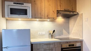 A kitchen with a built-in microwave, oven, and a stainless steel refrigerator. - Cozy Ski-In/Ski-Out Apartment with Fireplace, Sleeps 6, Balcony, Near Amenities (Les Orres)