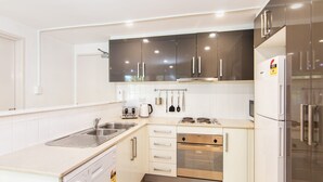 A modern kitchen with stainless steel appliances, white cabinetry, and a built-in oven.