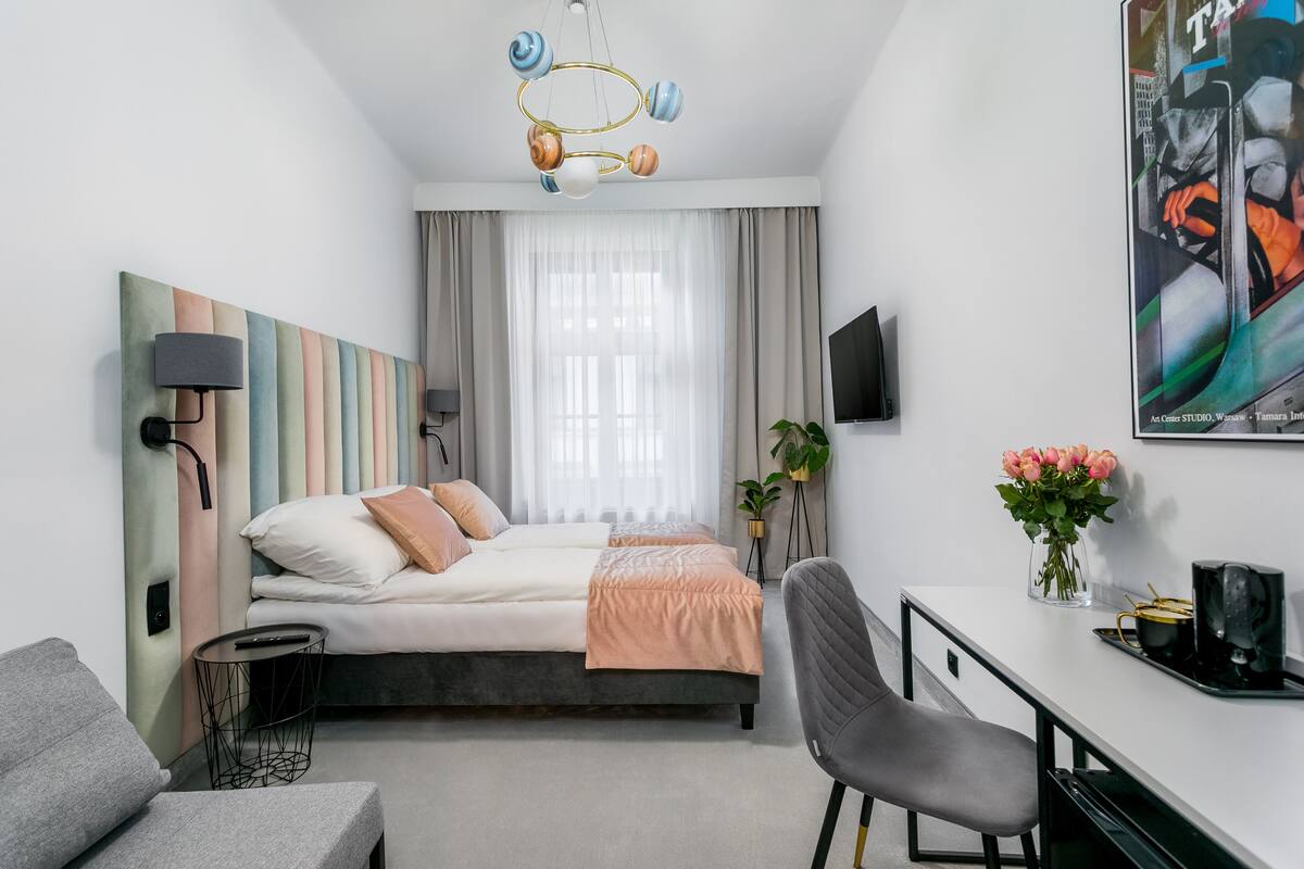Ein modernes Hotelzimmer mit Bett, Schreibtisch, Stuhl und einem großen Gemälde an der Wand.