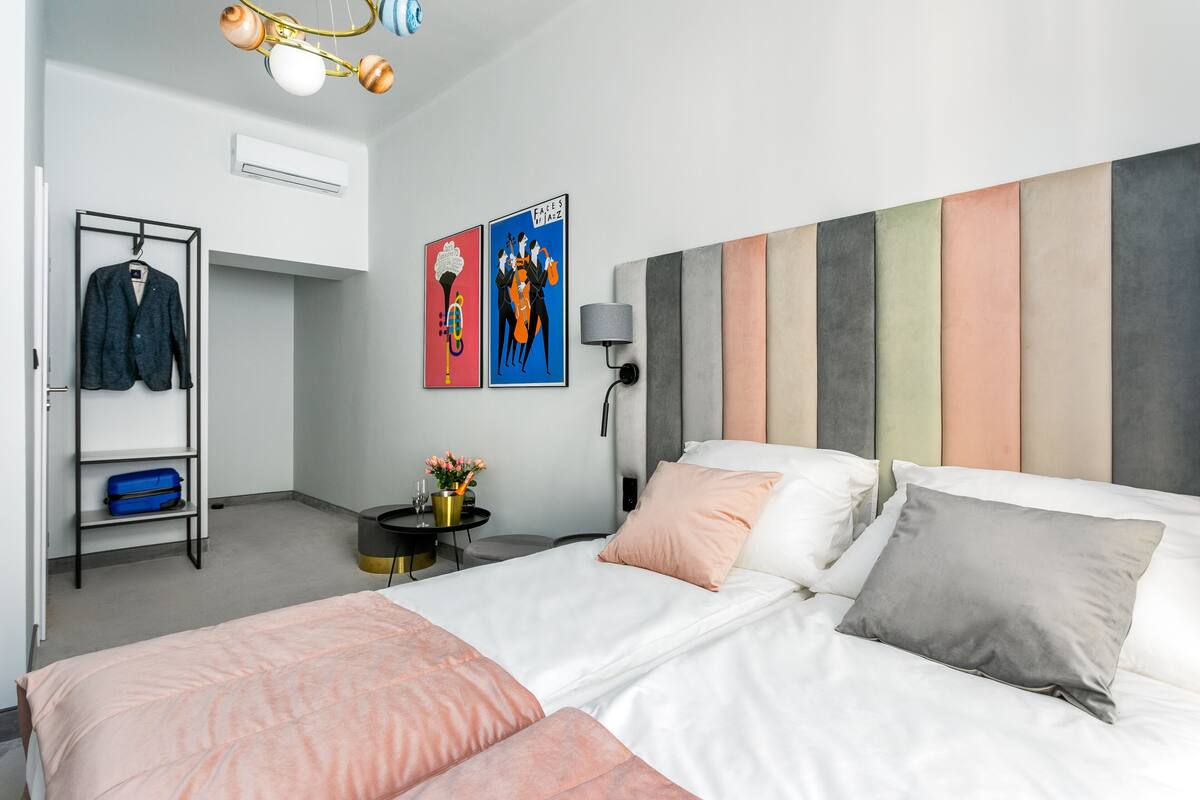 Ein modernes Hotelzimmer mit Bett, Nachttisch, Lampe und Kunstwerk an der Wand.