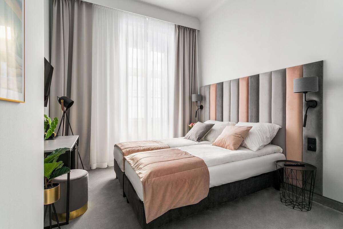 Ein modernes Schlafzimmer mit einem Bett, Nachttischlampen, einem Schreibtisch und einer Zimmerpflanze.