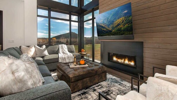 A modern living room with a fireplace, large windows, and a painting of a landscape.