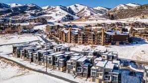 A modern hotel with a row of compact, multi-story buildings, set against a backdrop of snow-covered mountains.
