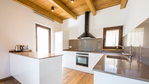 A modern kitchen with a central island, built-in oven, and a black range hood.